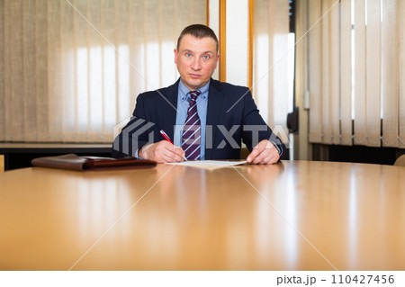 Middle aged man signing apply for job at meeting room 110427456