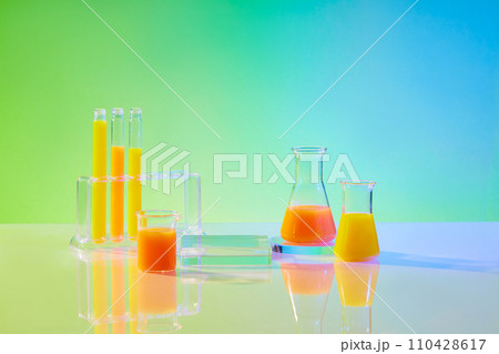 Science and medical background with lab glassware filled yellow liquid decorated on green gradient background. Lab theme, front view, space for display product, add text and design. 110428617