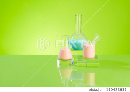Lab theme with lab equipments container color liquid displayed on transparent podium on a green background. Front view, space for display cosmetic product and copy space 110428631