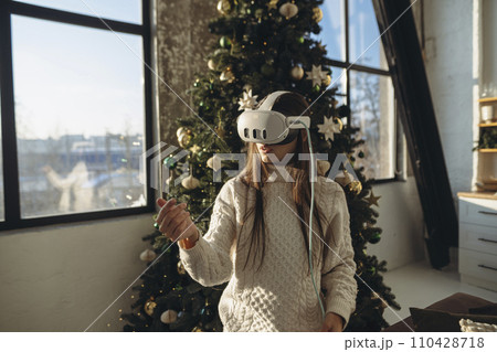 A captivating portrait of a girl adorned with a VR headset, framed by a Christmas tree. A captivating portrait of a girl adorned with a VR headset, framed by a Christmas tree. 110428718