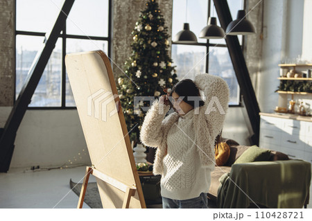 A cheerful ambiance: a vibrant young girl styles her hair for a Christmas party at home. 110428721