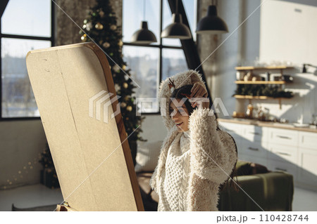 A bright young woman prepares her hairstyle for a Christmas gathering in her apartment. A bright young woman prepares her hairstyle for a Christmas gathering in her apartment. 110428744