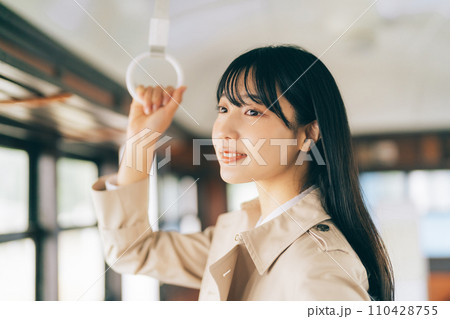 電車で吊り革を持つ女性 110428755