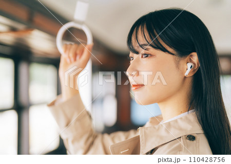 電車で音楽を聴く女性 110428756