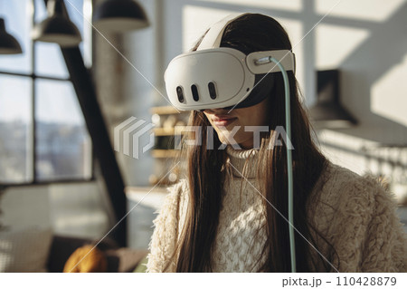 Embracing the sunny day, a bright young woman engages with a virtual reality headset. Embracing the sunny day, a bright young woman engages with a virtual reality headset. 110428879