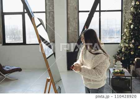 With a cheerful demeanor, a bright young woman in a Christmas reindeer mask brings smiles to the apartment. 110428920