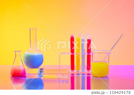 Close up of colorful liquids in test tubes and glass laboratory flasks on a pink yellow gradient background. Empty podium for product display with laboratory space. Close up of colorful liquids in test tubes and glass laboratory flasks on a pink yellow gradient background. Empty podium for product display with laboratory space. 110429178