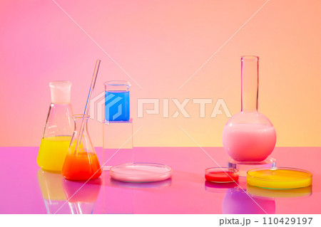 Lab setting with glassware holding colorful liquids on a pink-orange gradient background. Front view, ideal space for advertising and product development. 110429197