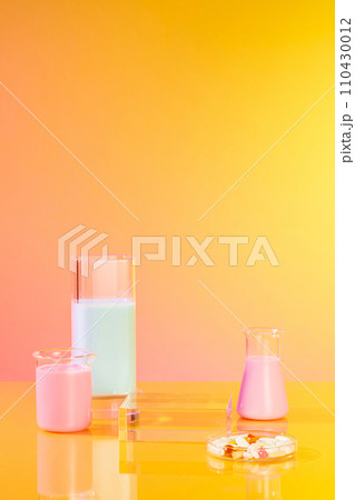 A handful of pills contained inside a petri dish, displayed with an empty podium and some glassware of pastel color liquid. Mock-up for exhibitions or presentation of cosmetic products or packaging 110430012