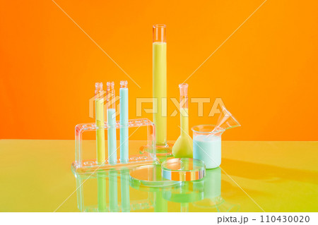 A stack of glass podiums in round shaped displayed with some laboratory glassware of blue and yellow liquid. Pedestal or platform for beauty products presentation A stack of glass podiums in round shaped displayed with some laboratory glassware of blue and yellow liquid. Pedestal or platform for beauty products presentation 110430020
