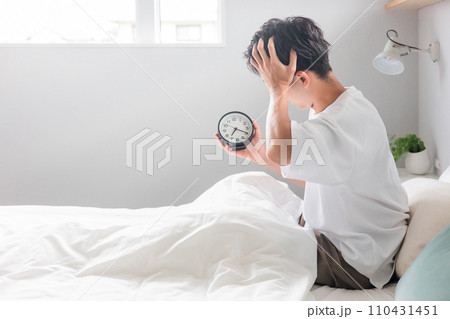 目覚まし時計を見て朝起床する男性(睡眠・覚醒・眠り) 目覚まし時計を見て朝起床する男性(睡眠・覚醒・眠り) 110431451