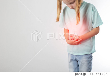 A little blonde girl of seven years old stands and holds her lower abdomen on a white background. Concept of diseases of the urinary system in children. Inflammation of the bladder, cystitis and A little blonde girl of seven years old stands and holds her lower abdomen on a white background. Concept of diseases of the urinary system in children. Inflammation of the bladder, cystitis and 110431507