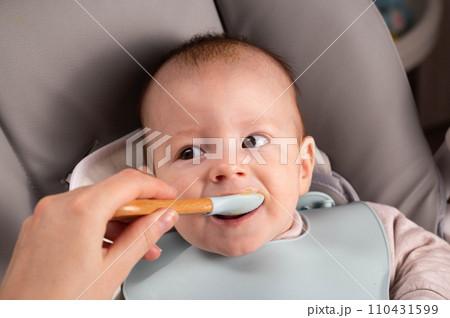 A little boy caucasian has been trying porridge and fruit puree for 6 months. Weight gain in infants, caloric content of food, close-up A little boy caucasian has been trying porridge and fruit puree for 6 months. Weight gain in infants, caloric content of food, close-up 110431599
