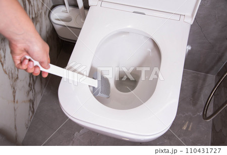 Modern silicone brush for cleaning the dirt of the wall-mounted toilet. Toilet care and hygiene concept, close-up 110431727