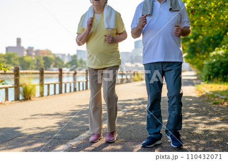 健康のためにウォーキングするアクティブシニアの男女夫婦　ダイエット　運動　散歩　逆光　夕方カラー 110432071