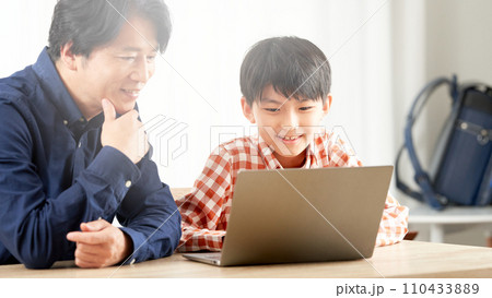 PCの画面を見つめる小学生の男の子と大人の男性 PCの画面を見つめる小学生の男の子と大人の男性 110433889