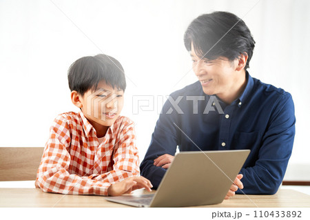 ノートパソコンの画面を見つめる男子小学生と大人の男性 ノートパソコンの画面を見つめる男子小学生と大人の男性 110433892