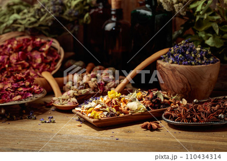 Various dried medicinal plants, herbs, and flowers on an old wooden background. 110434314