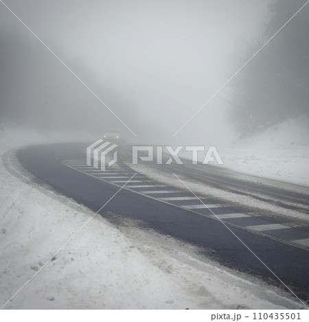 Bad weather driving - foggy hazy country road. Motorway - road traffic. Winter time. Autumn - fall. Snow and frost on the road in winter. Bad weather driving - foggy hazy country road. Motorway - road traffic. Winter time. Autumn - fall. Snow and frost on the road in winter. 110435501