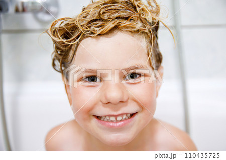 Cute child with shampoo foam and bubbles on hair taking bath. Portrait of happy smiling preschool girl health care and hygiene concept. Washes hair by herself. Cute child with shampoo foam and bubbles on hair taking bath. Portrait of happy smiling preschool girl health care and hygiene concept. Washes hair by herself. 110435725
