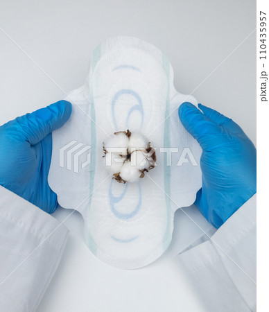 Sanitary napkin and cotton plant flower. A concept that shows the presence of plastic additives in sanitary pac, which cause redness, rash, and diaper rash in the female genital organs. 110435957