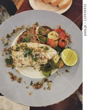 Grilled trout fish on a bed of quinoa with roasted vegetables and a lime wedge, healthy low-carb meal, vertical Grilled trout fish on a bed of quinoa with roasted vegetables and a lime wedge, healthy low-carb meal, vertical 110436452