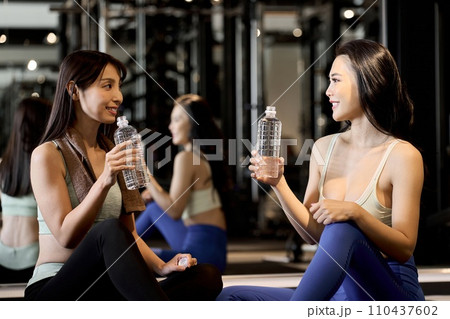 ジムで笑顔で話をする女性トレーニー ジムで笑顔で話をする女性トレーニー 110437602