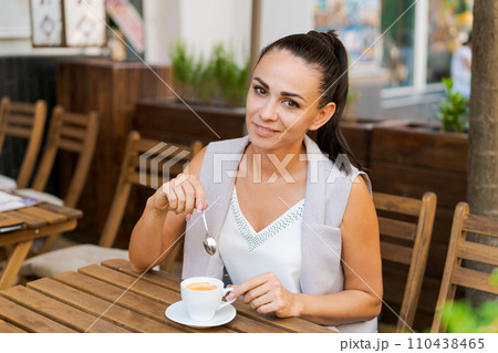 Happy smiling business brunette drinking coffee in a street cafe. Coffee break Happy smiling business brunette drinking coffee in a street cafe. Coffee break 110438465