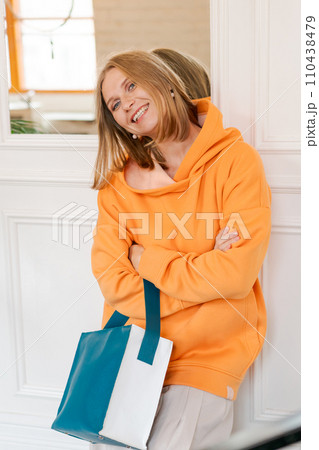 Portrait happy woman in cafe. Wearing a bright orange sweatshirt. 110438479