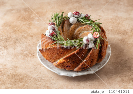 Christmas bundt cake decorated with glaze, cranberries and rosemary on beige table text space. Homemade cake recipe Christmas bundt cake decorated with glaze, cranberries and rosemary on beige table text space. Homemade cake recipe 110441011