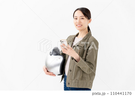 ヘルメットを抱えてスマートフォンを見る女性 110441170
