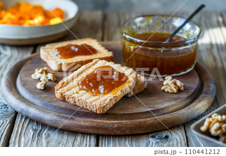 Rustic Pumpkin Jam Breakfast. Toasts with jam on wooden cutting board with jam jar 110441212