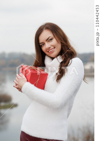 A young woman is holding a red box in her hands 110442453