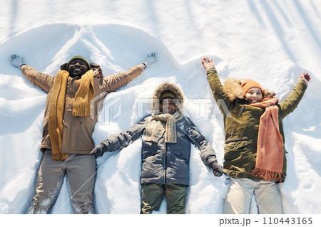 Family of three playing in snowdrift 110443165