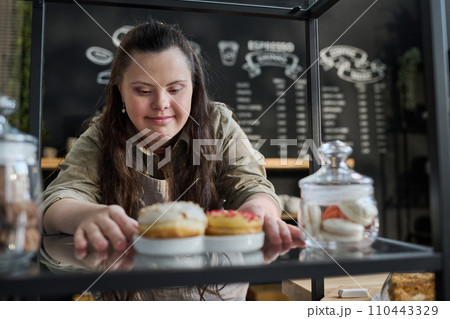 Waitress putting tasty donuts on tray 110443329