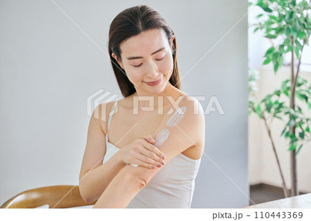 二の腕にクリームを塗ってボディケアする30代女性 110443369
