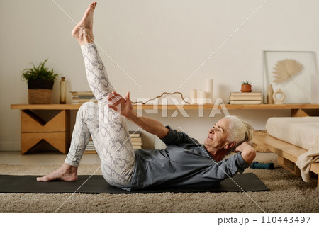 Woman stretching arm towards raised leg Woman stretching arm towards raised leg 110443497