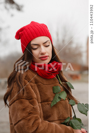 A young woman in a red hat and blanket with a bouquet of red roses 110443992