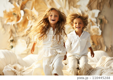 Cheerful children, sisters, brothers play and jump on the bed in the bedroom. 110445288