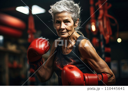 Mature elderly woman pensioner smiling happily doing boxing lifestyle for health in gym. 110445641
