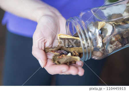 A hand pours homemade dry mushrooms into the hand close-up. The process of cooking mushrooms. 110445913