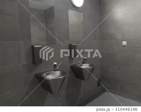 Modern stainless steel public toilet interior in the car park. Hand wash area with gray color ceramic tiles. Stainless washbasins 110446196