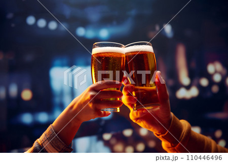 Two hands holding big mug of lager unfiltered foamy beer and clinking. Two friends sitting in bar and drinking alcohol drinks. 110446496