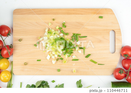 Top view of finely chopped green onions on a wooden cutting board. 110446711