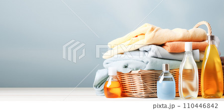 AI-generated content. Colorful clothes and towels in a wicker basket, various detergents for washing on a bright blue background AI-generated content. Colorful clothes and towels in a wicker basket, various detergents for washing on a bright blue background 110446842