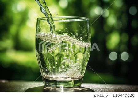Drink water pouring in to glass mug from water plastic bottle on green background. 110447020