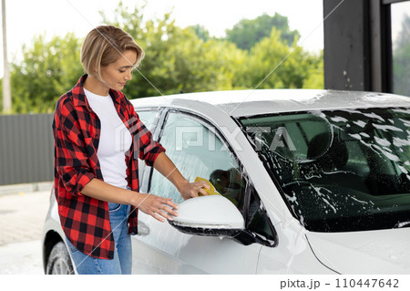 Woman in red shirt cleaning the car hood 110447642
