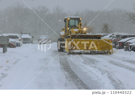 Tractor removes snow from road following snowfall in winter time Tractor removes snow from road following snowfall in winter time 110448322