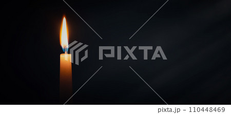 Candle burning in darkness over black background Candle burning in darkness over black background 110448469