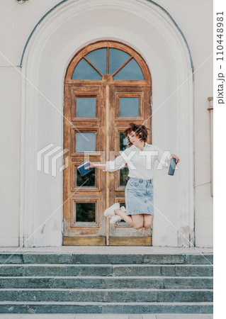 Woman staircase city. A business woman in a white shirt and denim skirt walks down the steps of an ancient building in the city 110448981